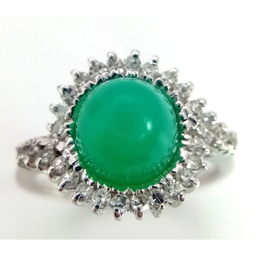 43 - An 18K White Gold, Diamond and Jade Cabochon Ring. A beautiful pale green jade cabochon with a diamo... 