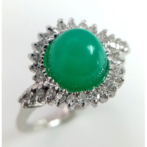 43 - An 18K White Gold, Diamond and Jade Cabochon Ring. A beautiful pale green jade cabochon with a diamo... 