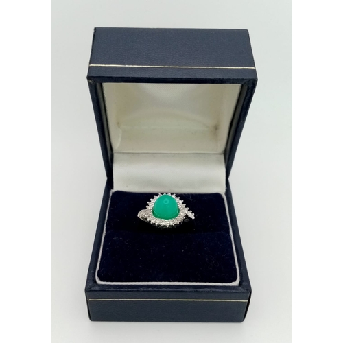 43 - An 18K White Gold, Diamond and Jade Cabochon Ring. A beautiful pale green jade cabochon with a diamo... 