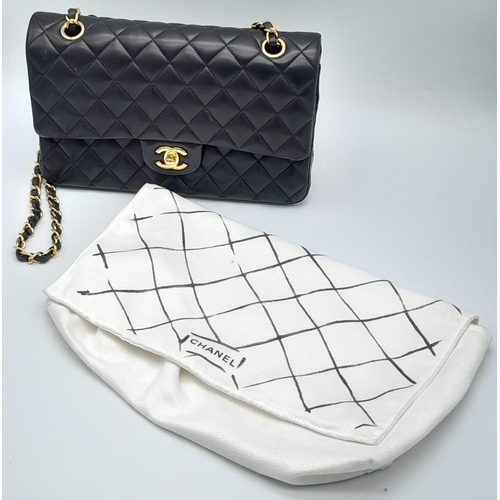 16 - A Classic Chanel Double Flap Bag. Quilted lambskin black leather exterior with gilded Chanel logo cl... 