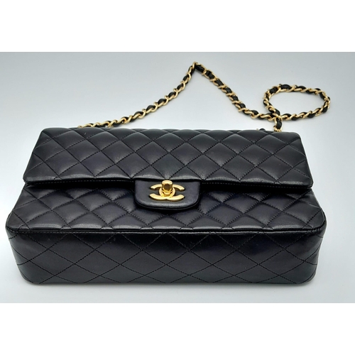 16 - A Classic Chanel Double Flap Bag. Quilted lambskin black leather exterior with gilded Chanel logo cl... 