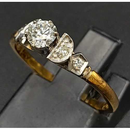 12 - An 18K Yellow Gold Diamond Ring. Central brilliant round cut diamond with two round cut diamonds on ... 