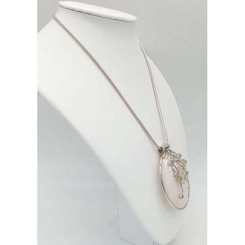 818 - A sterling silver snake chain with a very unusual large pendant made with Mother of Pearl and decora... 