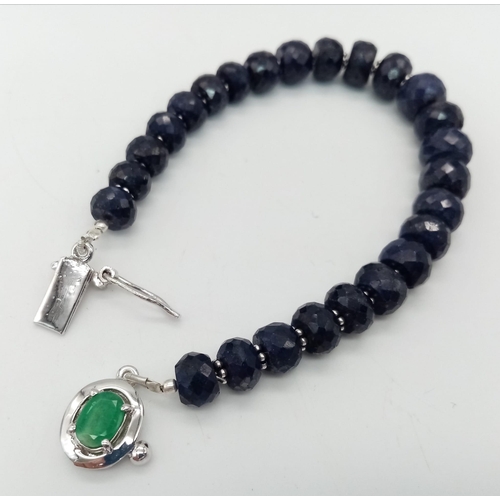 360 - A 140ct Blue Sapphire Rondelle Bracelet with Emerald and 925 Silver Clasp. 17cm.