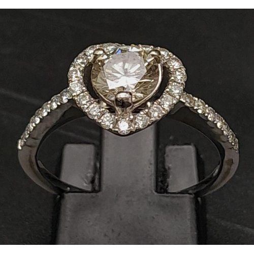 419 - An 18K White Gold Heart Shaped Diamond Ring. Central brilliant round cut diamond with a diamond hear... 