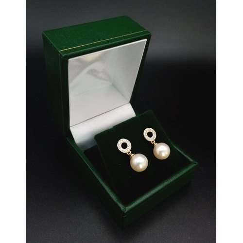 774 - A pair of 9K yellow gold cultured pearl droplet earrings with diamond halo bales. 0.15ct. Boxed. Ref... 