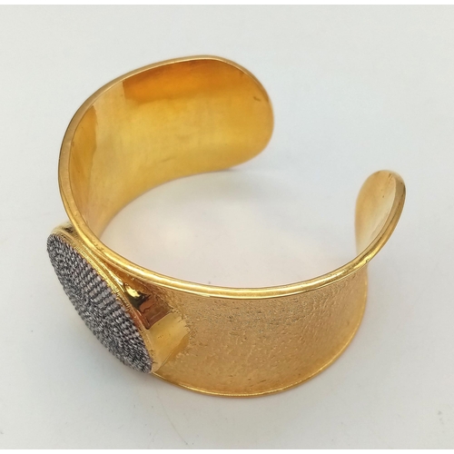 118 - A spectacular sterling silver and high carat gold covered bangle with a central medallion designed w... 