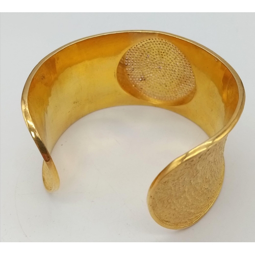 118 - A spectacular sterling silver and high carat gold covered bangle with a central medallion designed w... 