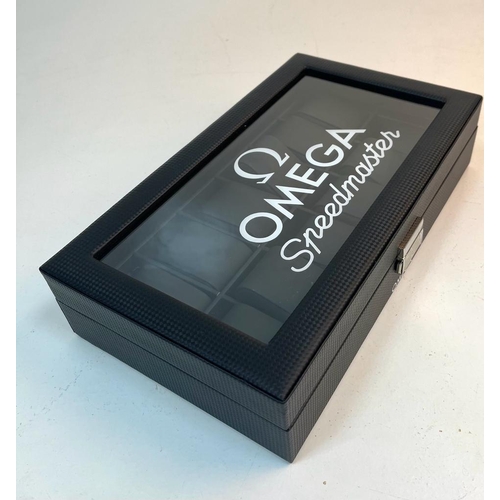 868 - A Twelve Watch Omega Display Case. Carbon fibre effect finish. Black felt on base. 52mm spaces. Plus... 