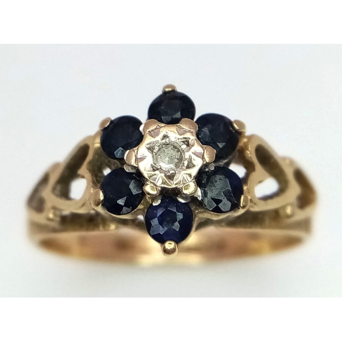 327 - A Vintage 9K Yellow Gold Sapphire and Diamond Ring. Central diamond with a halo of sapphires. Pierce... 