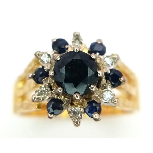 36 - An 18K Yellow Gold Diamond and Sapphire Ring. Central round cut sapphire with an alternating halo of... 