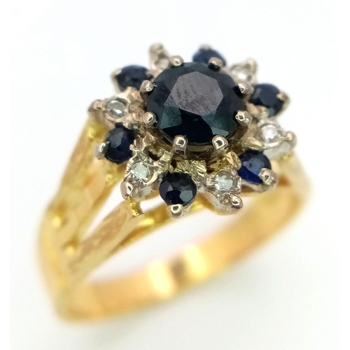 36 - An 18K Yellow Gold Diamond and Sapphire Ring. Central round cut sapphire with an alternating halo of... 