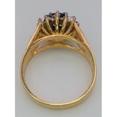 36 - An 18K Yellow Gold Diamond and Sapphire Ring. Central round cut sapphire with an alternating halo of... 