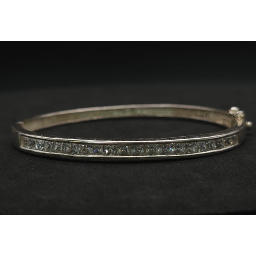 959 - Sterling silver channel set hinged bangle (diameter 6cm) with princess cut CZ stones, alongside a st... 