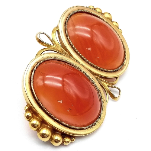 107 - An Antique 18K Yellow Gold (tested) and Carnelian Brooch. Two rich orange cabochons of carnelian set... 