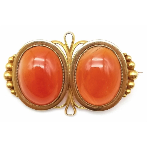 107 - An Antique 18K Yellow Gold (tested) and Carnelian Brooch. Two rich orange cabochons of carnelian set... 