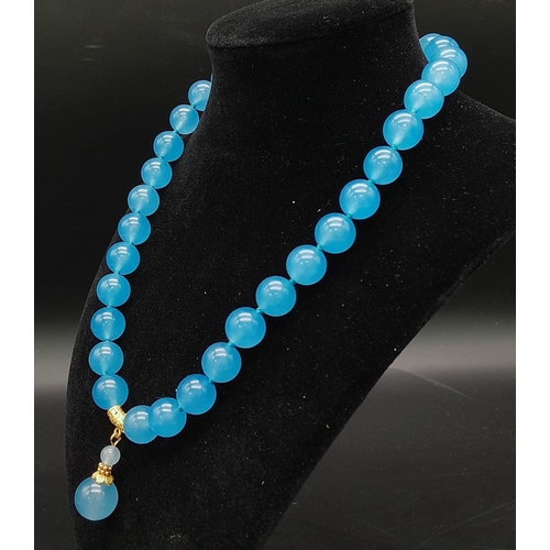 1038 - A Pale Blue Jade Bead Necklace with Hanging Jade Pendant. 12mm beads. Gilded clasp and accents. 44cm... 