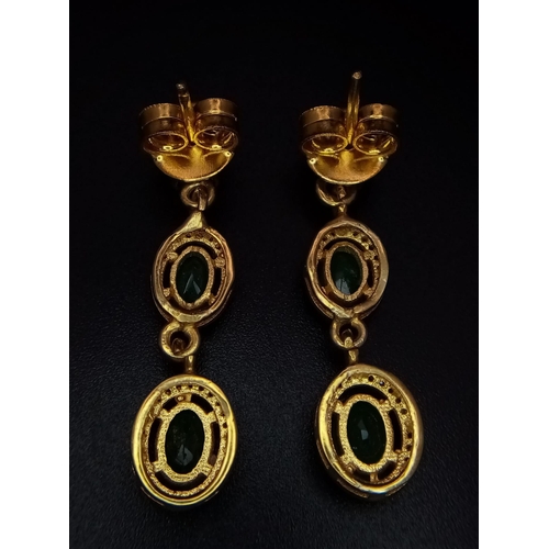 113 - An Edwardian pair of silver and gold earrings with emeralds and old cut diamonds presented in a beau... 