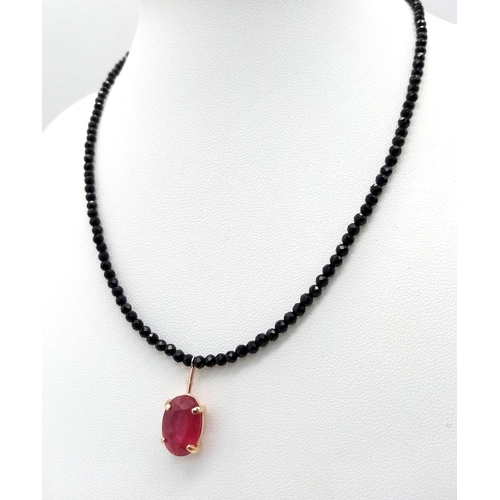 702 - A Black Spinel Small Bead Necklace with Hanging Ruby Decoration. 14k gold clasp. 38cm length