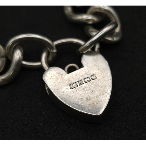 1016 - A Sterling silver chunky charm bracelet with heart padlock fastening. 31.6g