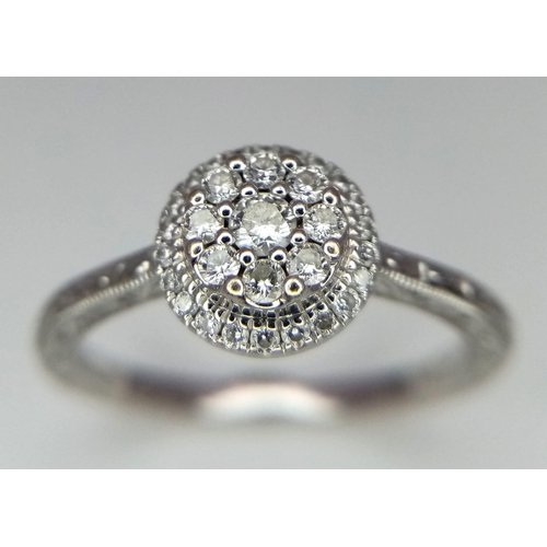 221 - An 18k white gold diamond halo cluster ring with engraved shoulders. 3.2g total weight.  Size N 1/2.... 