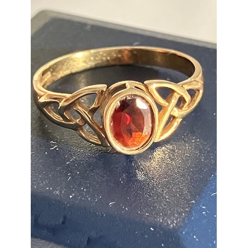 259 - 9 carat GOLD RING set to top with an oval cut GARNET. The band having attractive Celtic design Shoul... 