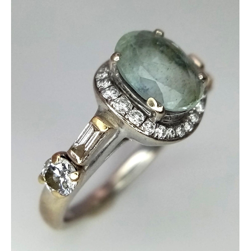 470 - A 14 K white gold ring with an oval cut aquamarine surrounded by a halo of round cut diamonds and fu... 