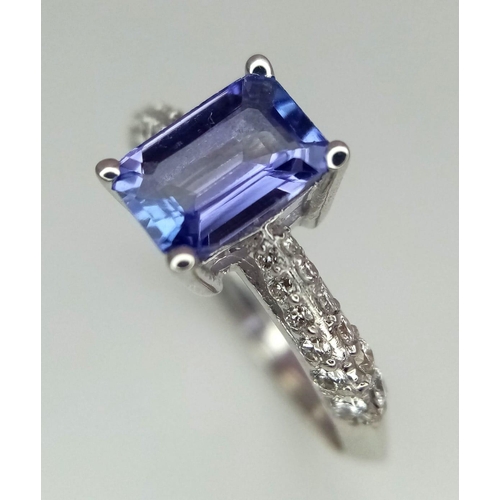 172 - An 18 K white gold ring with an emerald cut tanzanite (0.83 carats) and round cut diamonds on the sh... 