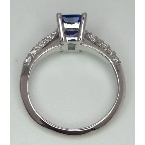 172 - An 18 K white gold ring with an emerald cut tanzanite (0.83 carats) and round cut diamonds on the sh... 