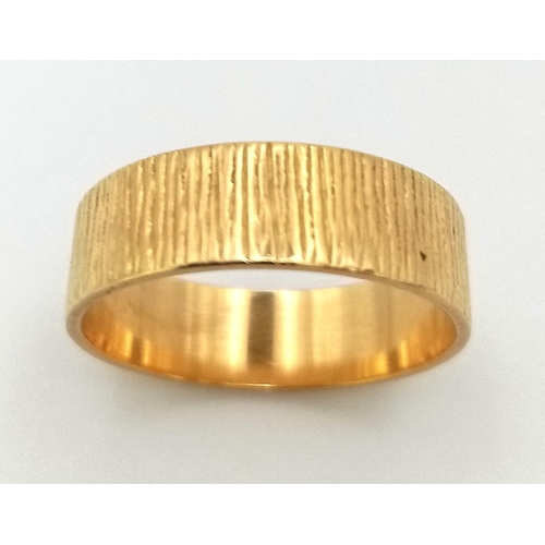 732 - AN 18K GOLD BAND RING WITH PATTERNED EXTERIOR .  3.9gms   size 0