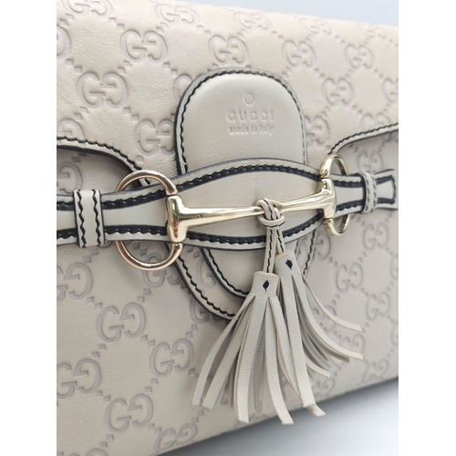 102 - A Gucci Beige 'Emily' Bag. Monogram leather exterior with buckle and tassels. A chunky and heavy set... 