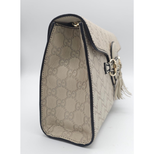 102 - A Gucci Beige 'Emily' Bag. Monogram leather exterior with buckle and tassels. A chunky and heavy set... 