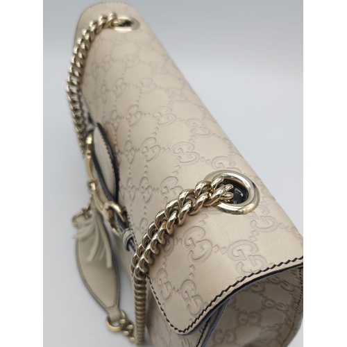 102 - A Gucci Beige 'Emily' Bag. Monogram leather exterior with buckle and tassels. A chunky and heavy set... 