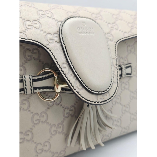 102 - A Gucci Beige 'Emily' Bag. Monogram leather exterior with buckle and tassels. A chunky and heavy set... 