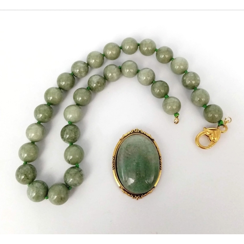 590 - A Green Jade Bead Necklace and Brooch. 14mm beads. 44cm necklace length with a gilded clasp. 5cm ova... 