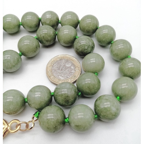 590 - A Green Jade Bead Necklace and Brooch. 14mm beads. 44cm necklace length with a gilded clasp. 5cm ova... 