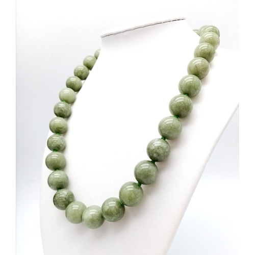 590 - A Green Jade Bead Necklace and Brooch. 14mm beads. 44cm necklace length with a gilded clasp. 5cm ova... 