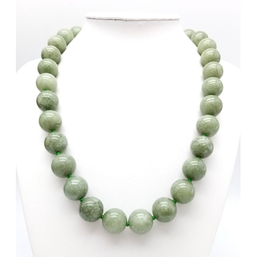 590 - A Green Jade Bead Necklace and Brooch. 14mm beads. 44cm necklace length with a gilded clasp. 5cm ova... 