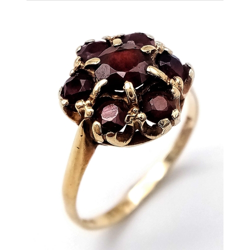 556 - A 9K YELLOW GOLD GARNET CLUSTER RING. Size P, 3g total weight.