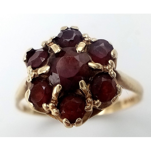 556 - A 9K YELLOW GOLD GARNET CLUSTER RING. Size P, 3g total weight.