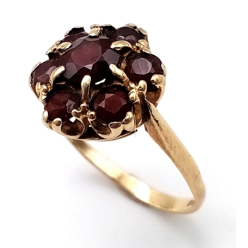556 - A 9K YELLOW GOLD GARNET CLUSTER RING. Size P, 3g total weight.