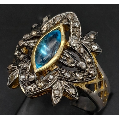 275 - A Gilded Silver Dress Ring with a Marquise Blue Topaz at Centre. Rub-over set topaz with a rose-cut ... 