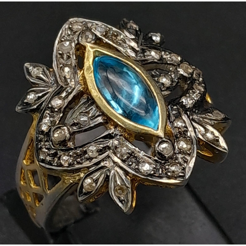 275 - A Gilded Silver Dress Ring with a Marquise Blue Topaz at Centre. Rub-over set topaz with a rose-cut ... 