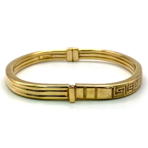 11 - A 9K GOLD ITALIAN DESIGNER HINGED BANGLE WITH GREEK PATTERN ON ONE SIDE . 10.2gms