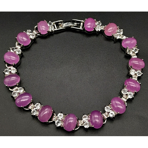 907 - A Pink Jade Tennis Bracelet with White Stone Spacers. 18cm.
Set in white metal.