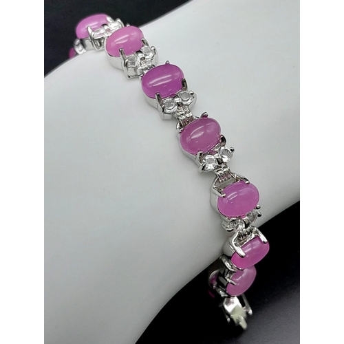 907 - A Pink Jade Tennis Bracelet with White Stone Spacers. 18cm.
Set in white metal.