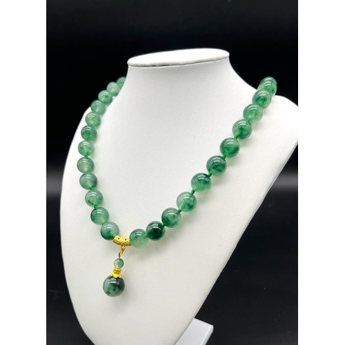 953 - A Green and White Jade Bead Necklace with Hanging Pendant. Gilded accents and clasp. Beads 12mm/14mm... 