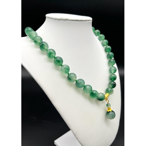 953 - A Green and White Jade Bead Necklace with Hanging Pendant. Gilded accents and clasp. Beads 12mm/14mm... 