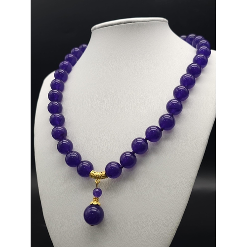 576 - A Purple Jade with Hanging Purple Jade Pendant. Gilded accents and clasp. 44cm necklace length. 12mm... 