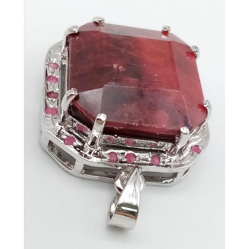 317 - An Octagon-Cut 128ct Ruby and 925 Silver Pendant. Large central stone with ruby surround. 4.5cm. 43.... 